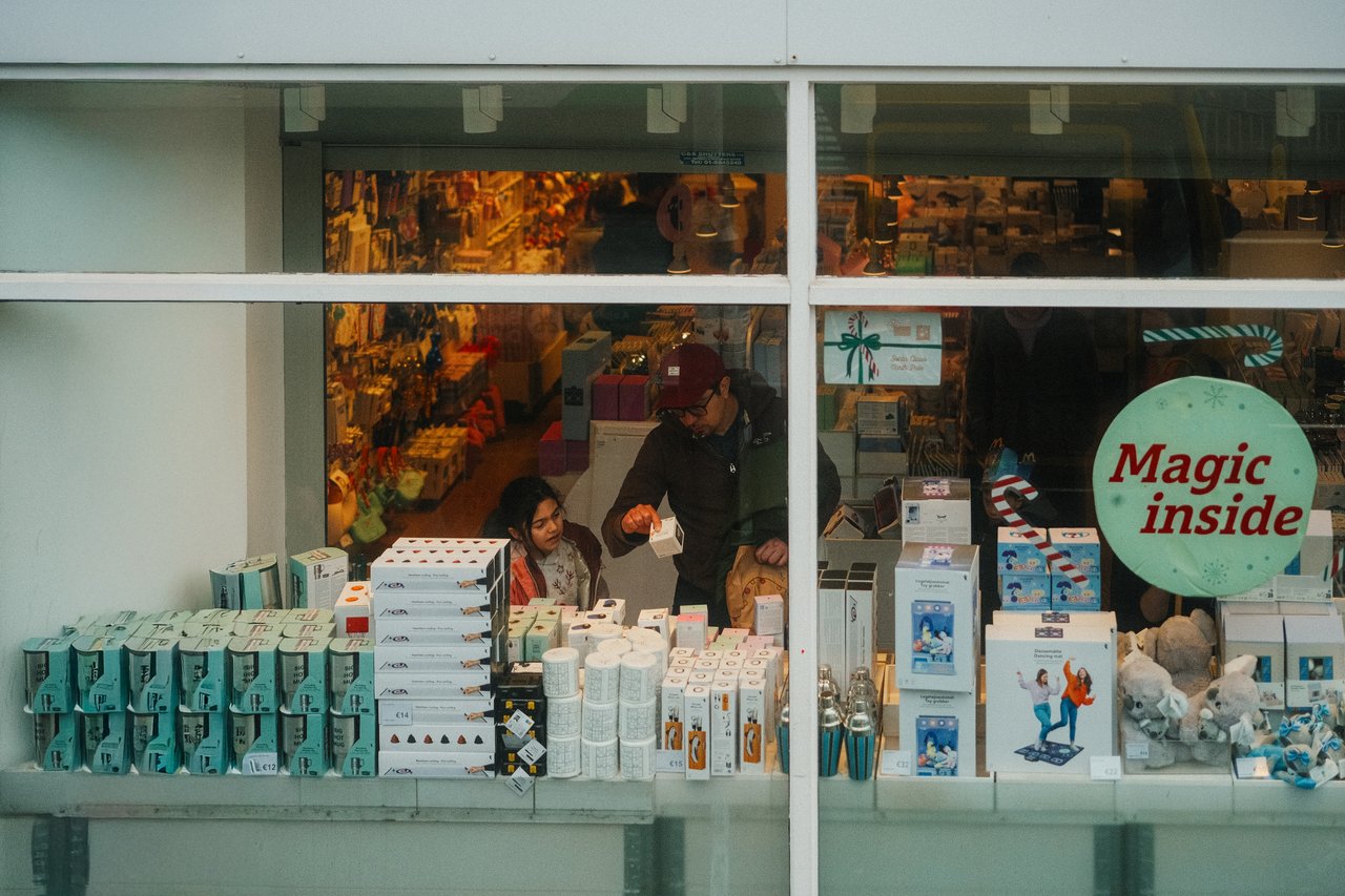 Father and daughter seen shopping inside a festive Dublin storefront, showcasing winter and holiday themes.